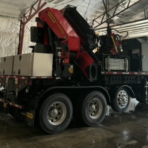 Knuckle-boom crane and Mecanil grapple saw mounted behind the cab of the crane truck