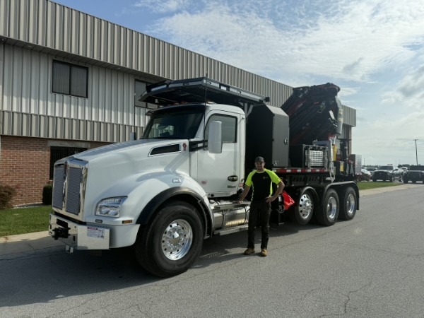 DL Tree Service crane truck parked outside with a crew member alongside it for scale