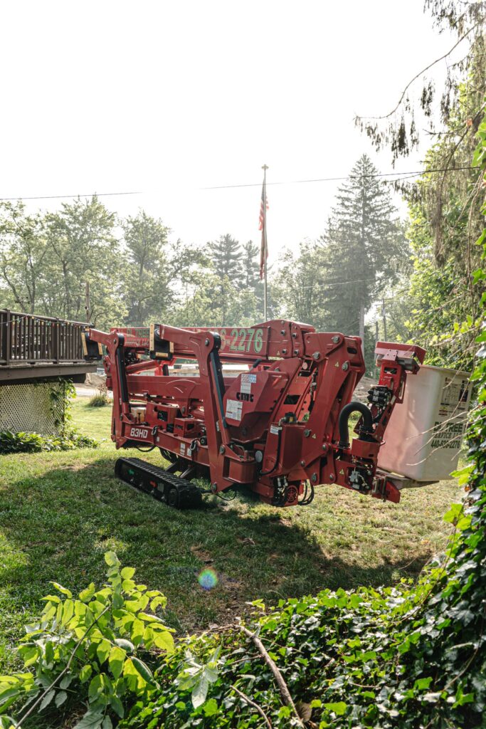 Tracked spider lift staged on a residential lawn before a tree removal